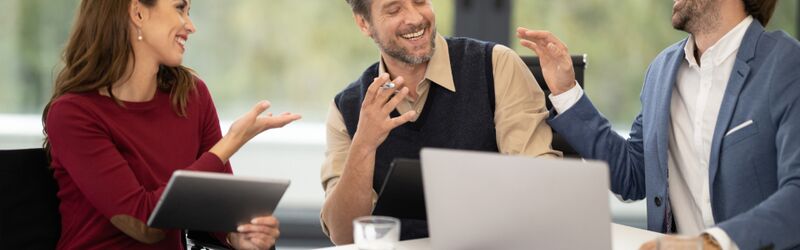 Three colleagues reviewing results together around a table with a laptop and a tablet