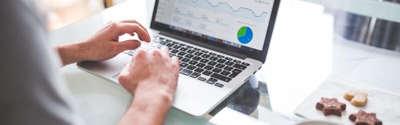 A person working at a laptop that displays a revenue trend line and a margin breakdown chart